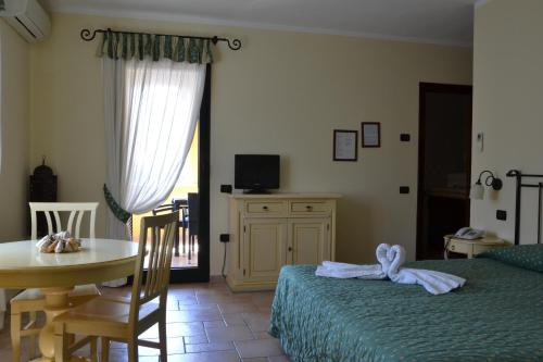 a bedroom with a bed, chair, table and television at Hotel Villa Del Parco in La Maddalena
