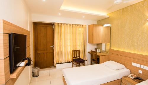 a bedroom with a bed and a desk and a chair at Hotel Kapilavasthu in Palakkad