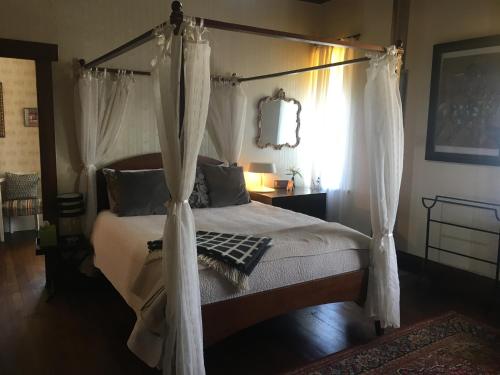 a bedroom with a canopy bed with white curtains at The Inn At The Convent in Taumarunui