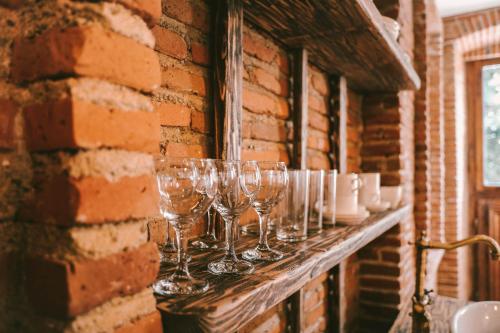 a row of wine glasses on a brick wall at Old Chache House in Tʼelavi