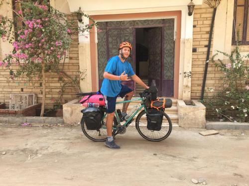 a man standing next to a bike in front of a house at david hostel in Aswan
