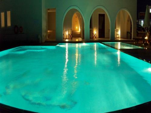 a large swimming pool with blue lighting in a building at Perla Hotel in Agios Prokopios