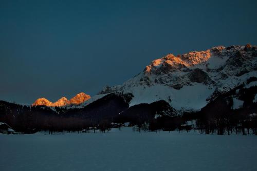 a snow covered mountain at night with the lights on at Naturhotel Lärchenhof in Ramsau am Dachstein