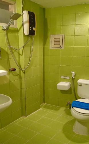 a green bathroom with a shower and a toilet at Sawasdee Sukhumvit Inn in Bangkok