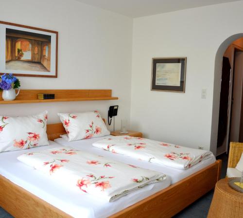 a bedroom with two beds with white sheets and red flowers at Hotel Ebnet Garni in Lindau