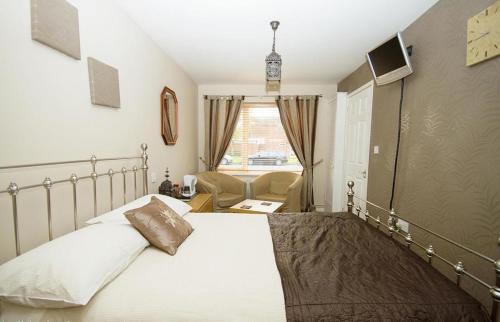 um quarto com uma cama, uma cadeira e uma janela em Warwick Home From Home em Warwick