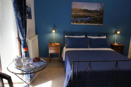 B&B Liolà في أغريغينتو: غرفة نوم زرقاء مع سرير وطاولة زجاجية