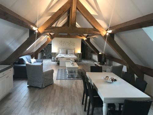 a attic room with a bed and a table and chairs at Cense de Lalouette in Saint-Ghislain