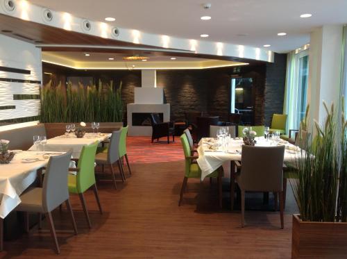 a dining room with white tables and green chairs at Superior Hotel Nidwaldnerhof in Beckenried