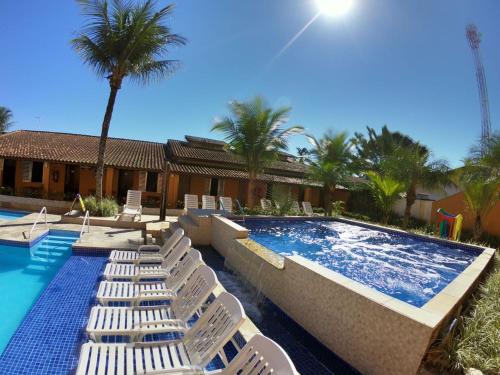 a swimming pool with white lounge chairs and a swimming pool at Pousada Costa da Riviera PISCINA CLIMATIZADA in Bertioga
