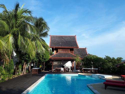 una piscina di fronte a una casa con un edificio di Sari Village Jungle Retreat a Pantai Cenang