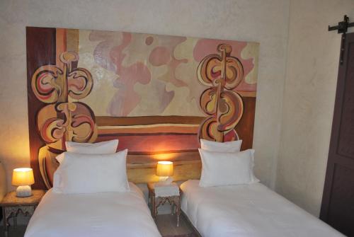 two beds in a room with a painting on the wall at Casa Taos in Marrakech