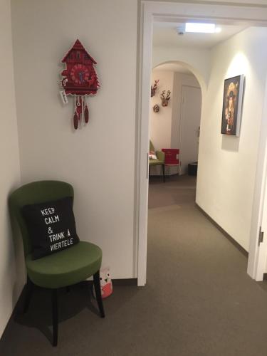 a hallway with a green chair and a wall with a clock at Hotel Restaurant Der Engel, Sasbachwalden in Sasbachwalden