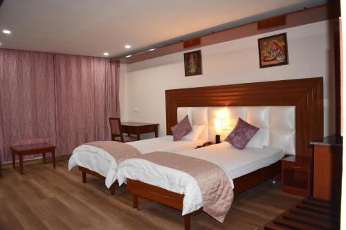 a hotel room with two beds and a television at Hotel Sujata in Bodh Gaya