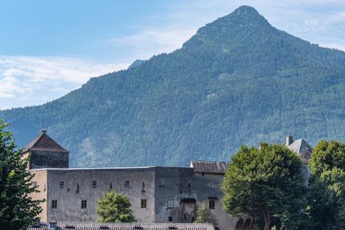 an old building with a mountain in the background at Gasthof Hotel Hauslwirt in Golling an der Salzach