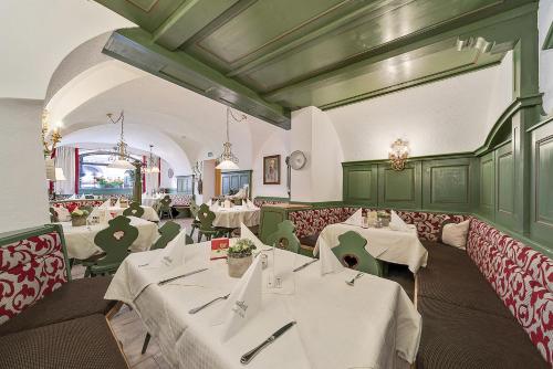 a restaurant with white tables and green booths at Gasthof Hotel Hauslwirt in Golling an der Salzach