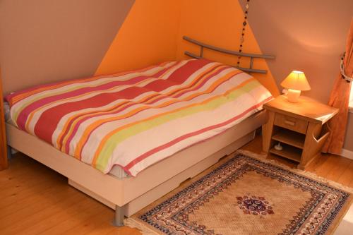 un letto con un piumone colorato a righe in una stanza di A la Pavée a Péruwelz