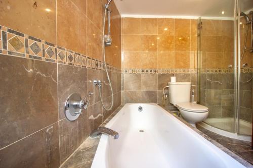 ein Bad mit einer Badewanne und einem WC in der Unterkunft Art Apartment In Mamila in Jerusalem