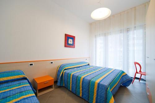 a bedroom with two beds and a red chair at Quadrangolo in Bibione