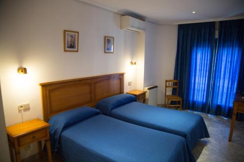 Habitación de hotel con cama azul y ventana en Hostal Acuario, en Gálvez