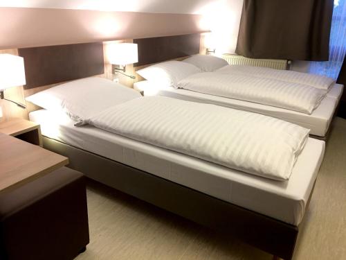 two beds in a hotel room with white pillows at Hana Aparthotel in Hamburg