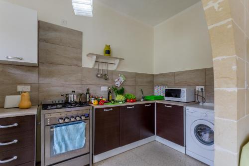 a kitchen with a stove and a washer and dryer at Serenity - Bellevue Gozo in Xlendi