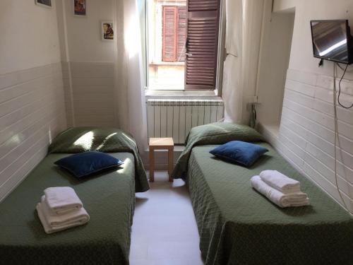 2 Betten in einem kleinen Zimmer mit Handtüchern darauf in der Unterkunft Oscar Rooms in Rom