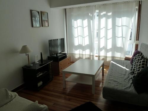 a living room with a couch and a table and a tv at Amplio, Luminoso y Céntrico Piso in A Coruña