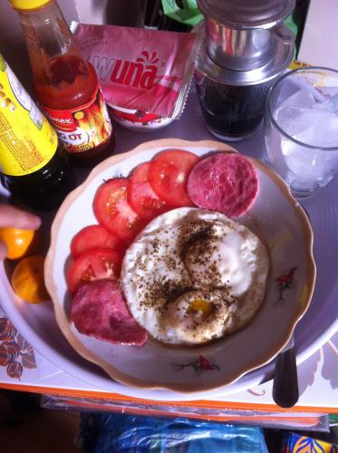 a plate of food with a fried egg and tomatoes at Ban Mai Hotel 66 in Phan Thiet