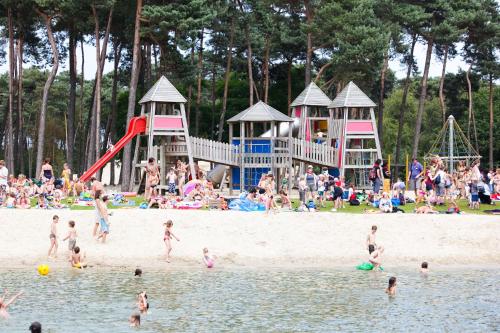 a group of people on a beach with people playing in the water at De Spreekkamer in Hoogstraten
