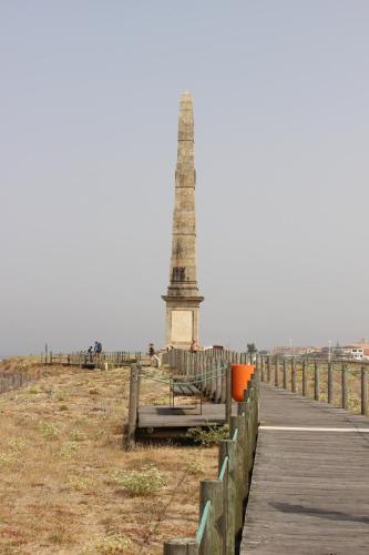 a monument on the beach with a bench and a boardwalk at Matosinhos -Seas Apartment- Cabo das Marés in Matosinhos