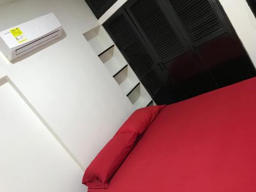1 dormitorio con cama roja y aire acondicionado en Santa Marta Apartamentos Salazar - Maria Paula, en Santa Marta