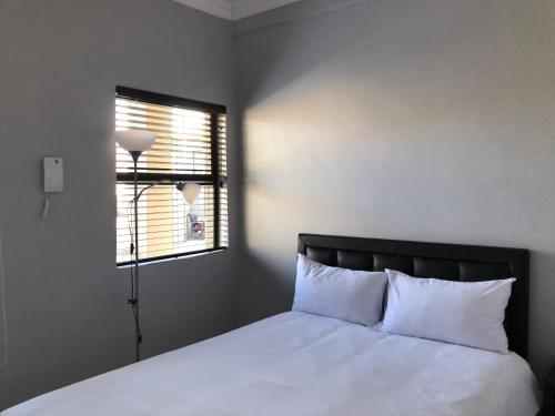 a bedroom with a bed with white sheets and a window at Sunflower Guesthouse in Vanderbijlpark