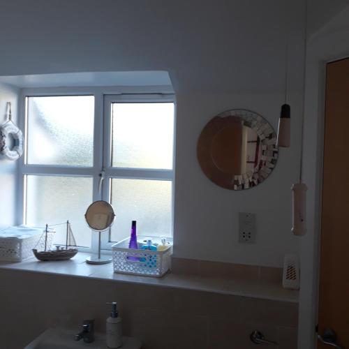 a bathroom with a sink and a mirror and a window at Roneragh Apartments Paul's place The Only Penthouse Apartment in Fahan