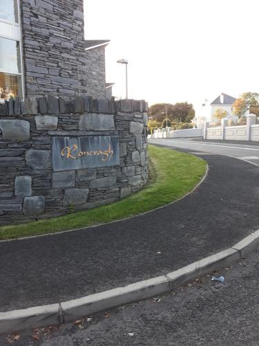 a stone wall with a sign on the side of a road at Roneragh Apartments Paul's place The Only Penthouse Apartment in Fahan