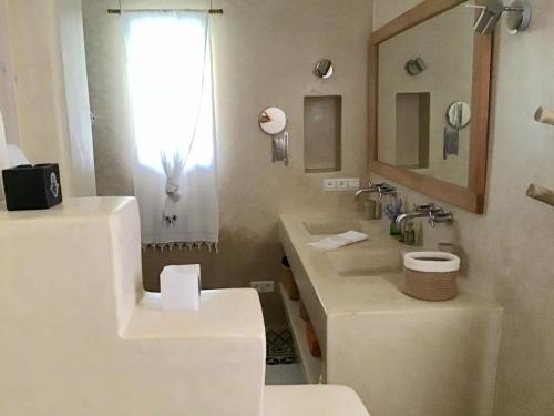 a white bathroom with a sink and a mirror at Dar Alya Essaouira Maison et table d'hôtes in Ghazoua