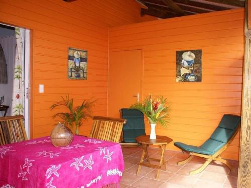an orange room with a table and chairs on a porch at Villa Manguier in Rivière-Salée