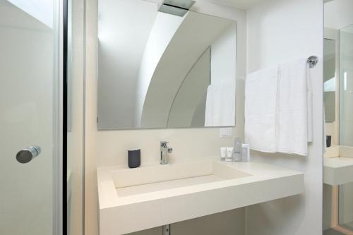 a white bathroom with a sink and a mirror at B&Bari, via Cairoli - guesthouse Le Case di Aurelia in Bari