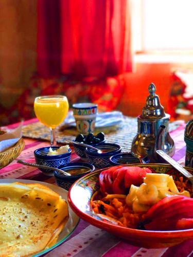 a table with plates of food and a glass of orange juice at Auberge Ayouze in Aït Ben Haddou