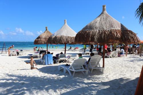 a group of people sitting on a beach with umbrellas at The Diving Lodge Downtown in Puerto Morelos