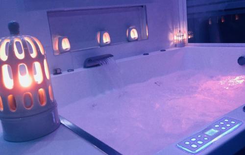 eine Fernbedienung in einer Badewanne mit Kerzen in der Unterkunft Appart' Spa et Sauna Privatif Au Cœur De Beaune in Beaune