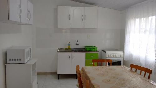 una pequeña cocina con mesa y microondas en Casa em Mariscal - 5 a 8 pessoas, en Bombinhas