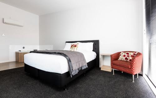 a bedroom with a bed and a red chair at Zachary's Motel in Levin