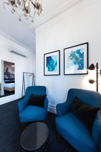 a living room with two blue chairs and a bed at East Brunswick Hotel in Melbourne