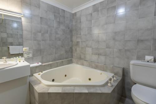 een badkamer met een bad, een toilet en een wastafel bij Club Inn Motel in West Wyalong