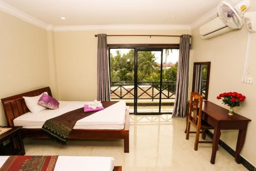 a bedroom with a bed and a desk and a window at Blue Diamond Hostel in Battambang