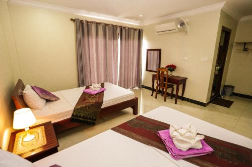 a hotel room with two beds and a table at Blue Diamond Hostel in Battambang