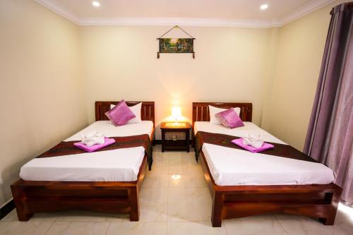 two beds in a room with pink pillows on them at Blue Diamond Hostel in Battambang