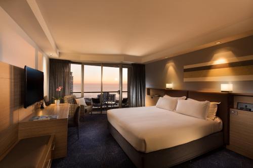 a hotel room with a bed and a living room at Sofitel Gold Coast Broadbeach in Gold Coast