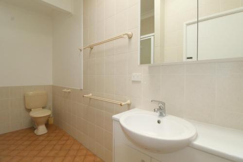 a white bathroom with a sink and a toilet at Beachfront 6, 25 Willow Street in Crescent Head